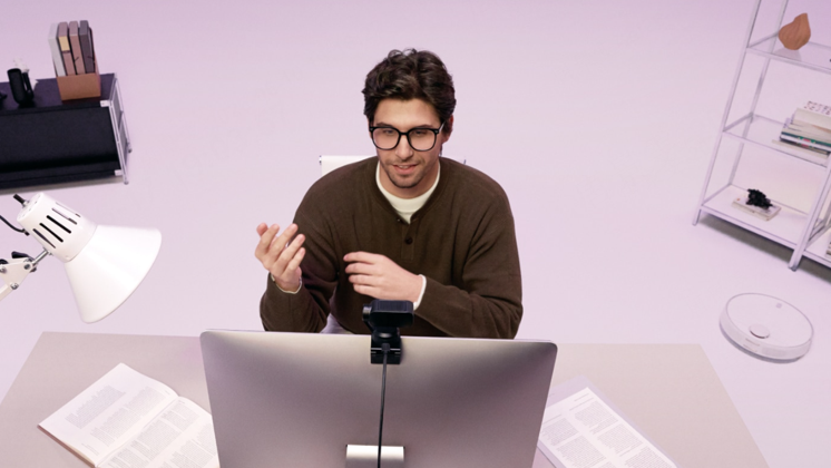 A man speaks at his desk, presenting with an Insta360 Link 2 AI webcam.